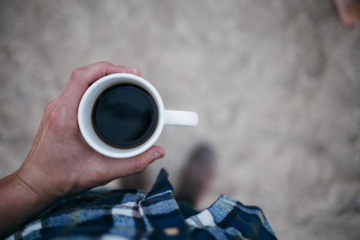 Hand holding a small cup of black coffee before a workout