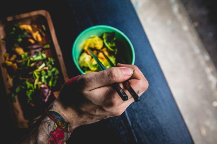Bowl of healthy food eaten with chopsticks on a dark table