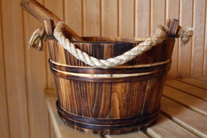 Wooden sauna bucket with rope handle on a sauna bench