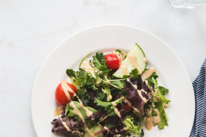 Fresh salad plate with water glass on a marble table