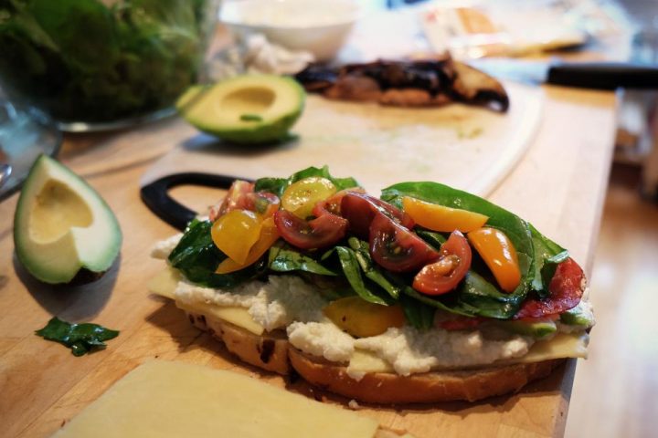 Open-faced sandwich with tomatoes and greens on a kitchen counter