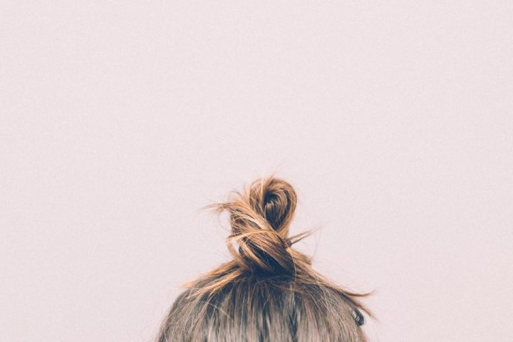 Top of a woman's head with hair in a loose bun, showing scalp and crown