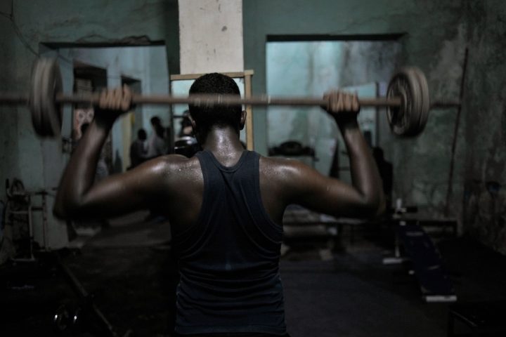 Man pressing a barbell overhead during a gym workout